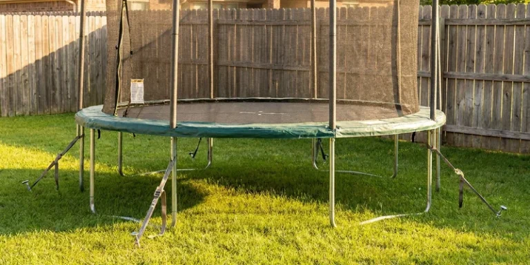 trampoline ground anchors: trampoline with safety net in a backyard